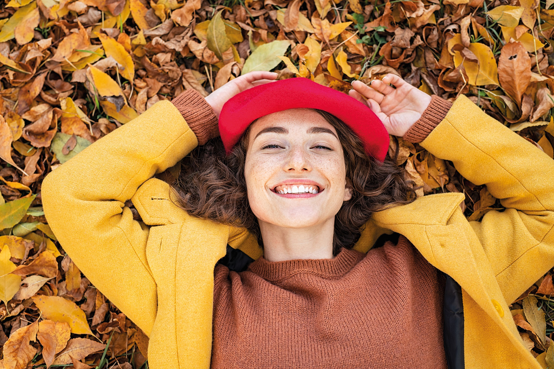 Frau auf Laub liegend im Herbst